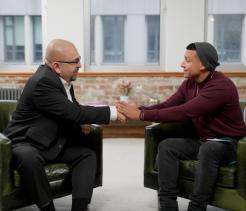 Two men in seated positions shaking hands