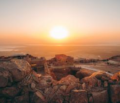 Sunrise over ancient desert ruins overlooking a vast arid landscape.