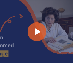 Video thumbnail titled Iran Loomed Large showing an older woman seated at a table reviewing photographs and documents, with a play button overlay.