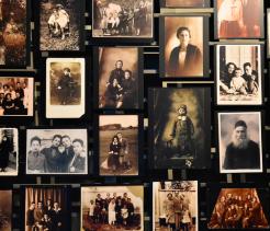 A large display of vintage black-and-white and sepia family photographs arranged in rows, showing men, women, and children from different generations, many wearing early 20th-century European clothing, suggesting everyday Jewish life and family connections before the Holocaust.
