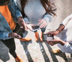 Group of three young adults on smartphones. 