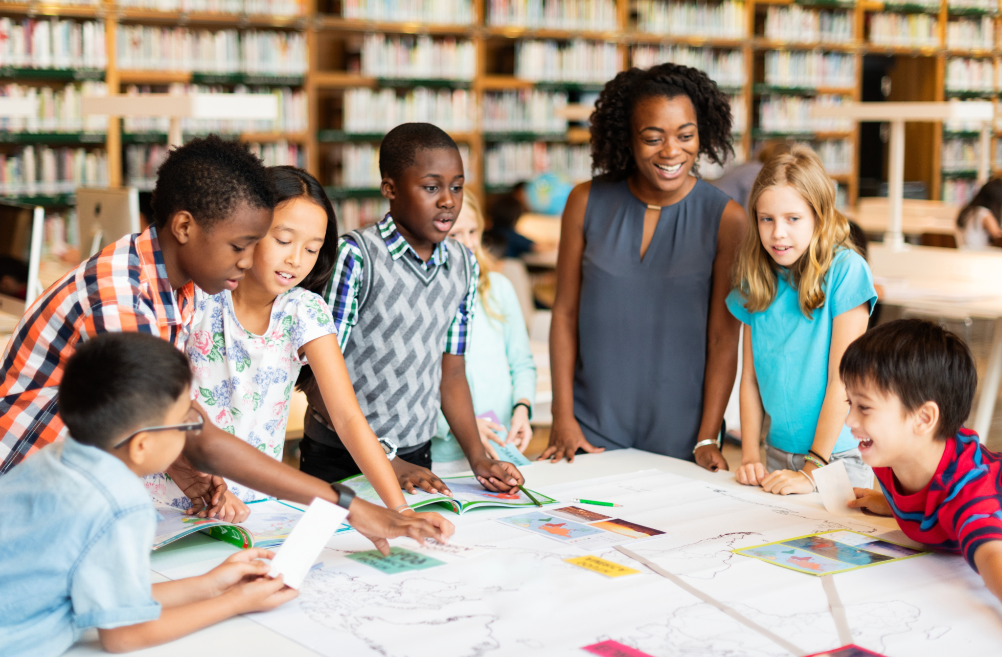 Teacher and students looking at materials on the table and laughing.