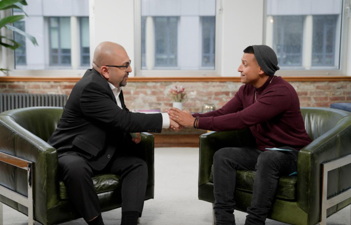 Two men in seated positions shaking hands